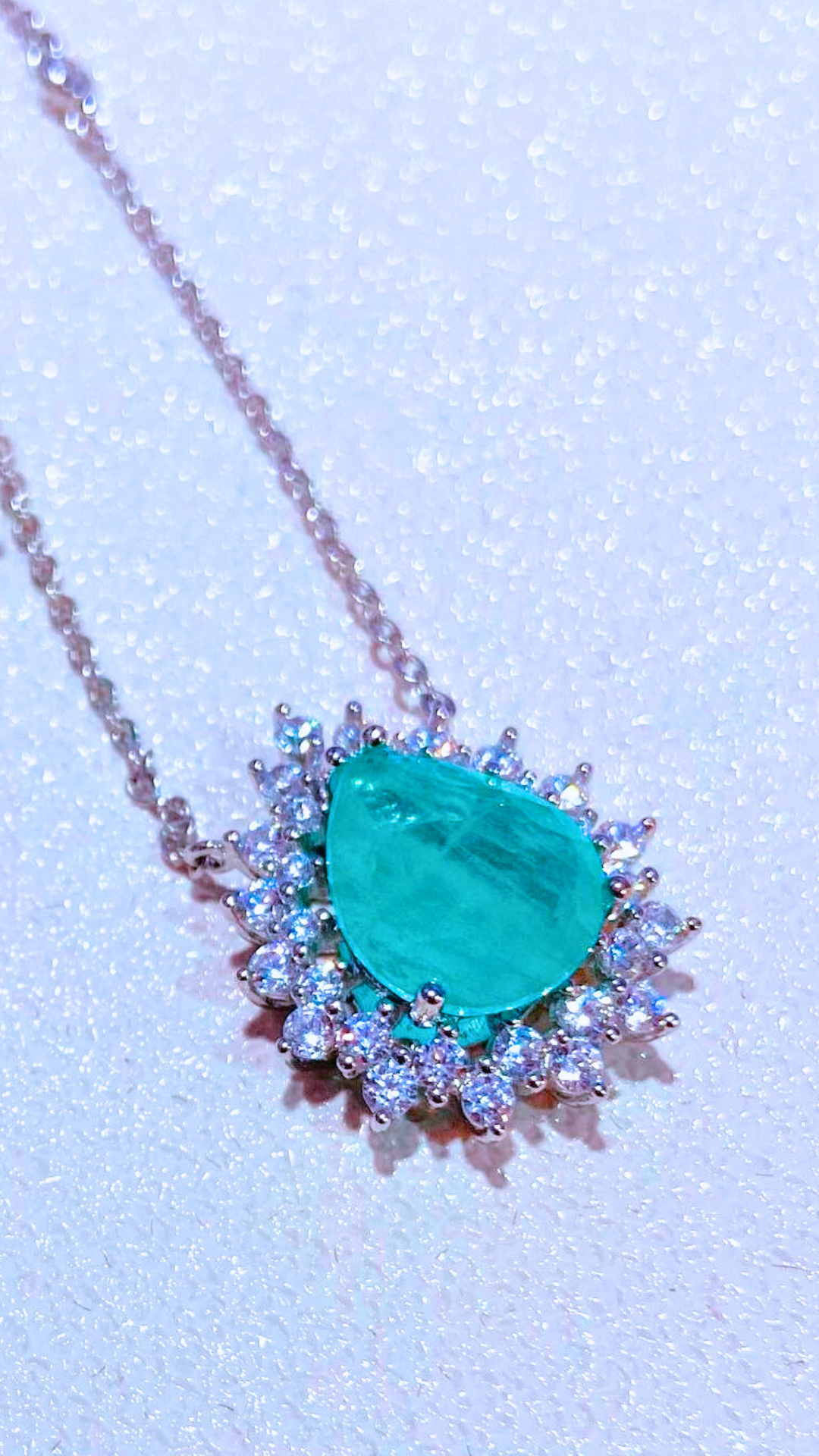 Green tourmaline necklace with a pear-shaped stone surrounded by a cubic zirconia crown on a white background.