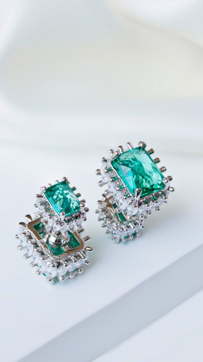 Two silver rings featuring green tourmaline gemstones surrounded by small cubic zirconia diamonds