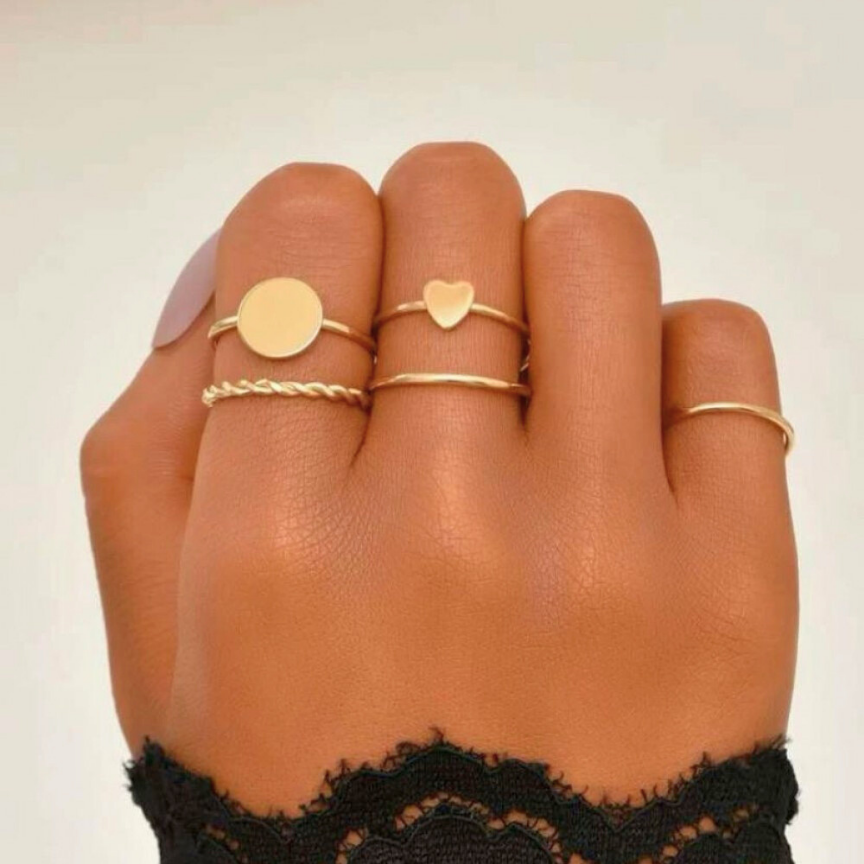 Hand adorned with multiple gold rings, including the Mymore Jewellery Minimalist Ring, showcasing a delicate twisted design in 18k gold plating. The rings are worn on different fingers, highlighting their elegant and versatile style.